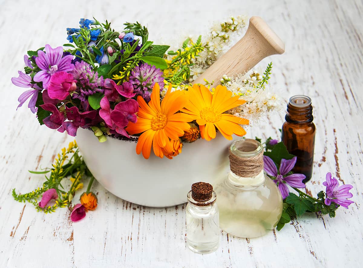mortar and pestle with fresh flowers and apothecary bottles
